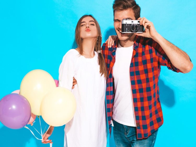 Kolorowa sesja pary w studiu – kobieta z balonami i mężczyzna z aparatem na niebieskim tle, Fotografia Olivia