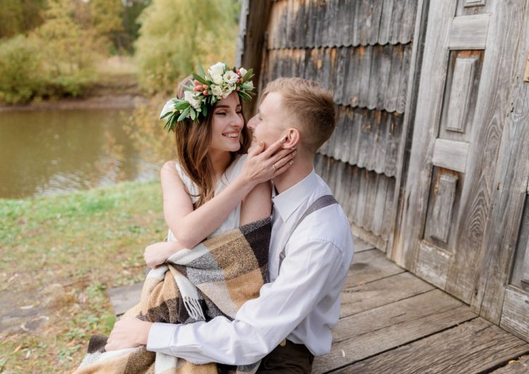 Para zakochanych przytulona na drewnianym pomoście, kobieta z wiankiem kwiatowym na głowie